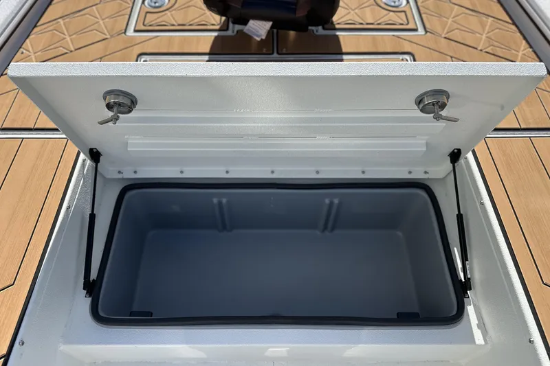 Slide: The Image of Open storage compartment on Avid 207 Recon boat, 2026 model, with wooden deck background. - 26