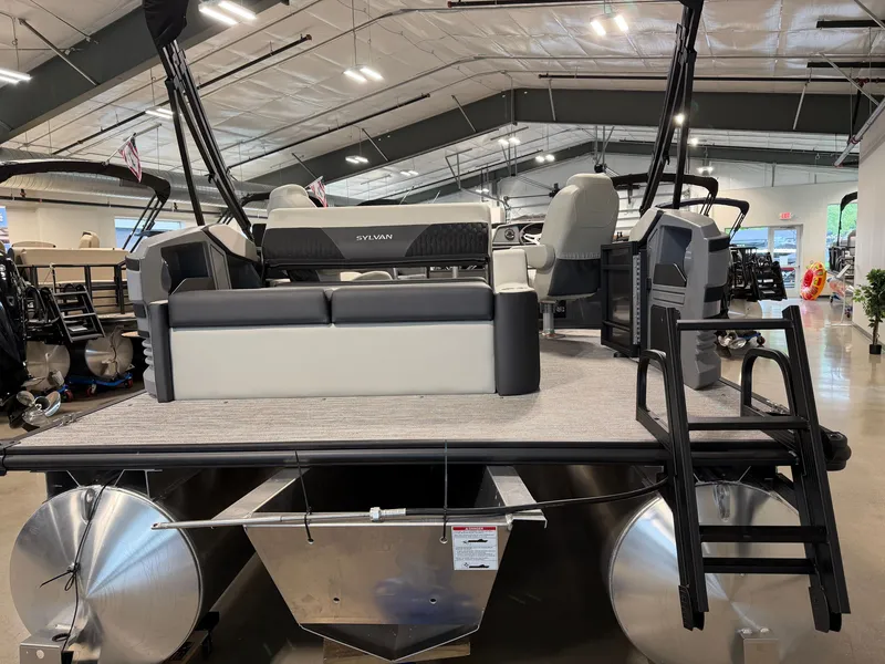 Slide: The Image of The image shows a 2027 Sylvan R-20 Q DH pontoon boat in a showroom. It features gray upholstery and a sturdy aluminum hull. - 3