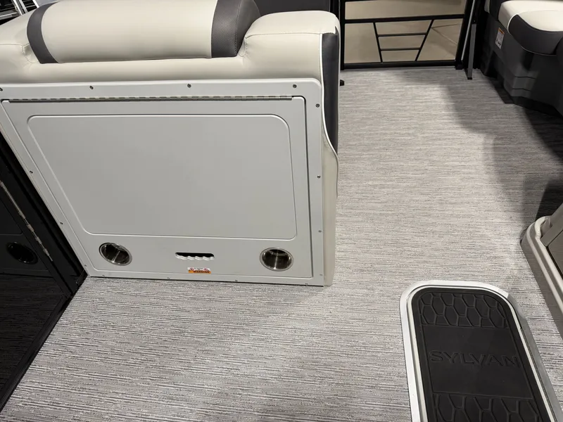 Slide: The Image of Interior of a 2026 Sylvan MIRAGE X3 DLZ BAR with gray carpet and cushioned seating. - 24