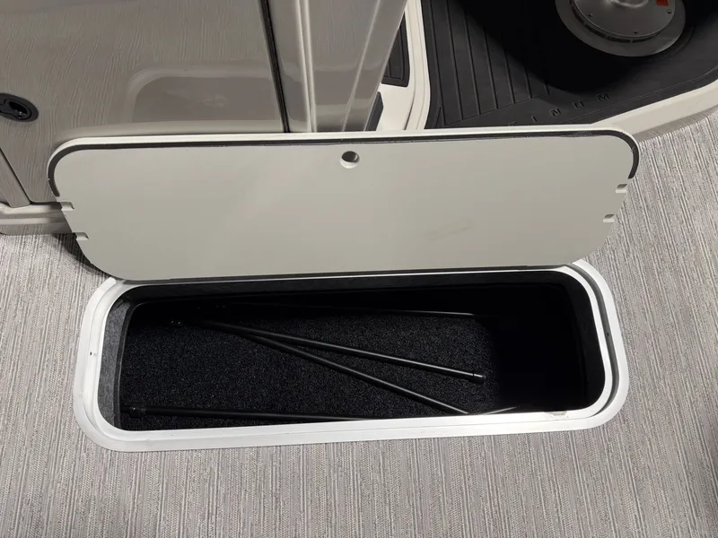 Slide: The Image of An open storage compartment on a boat with gray carpeting and black rods inside. - 13
