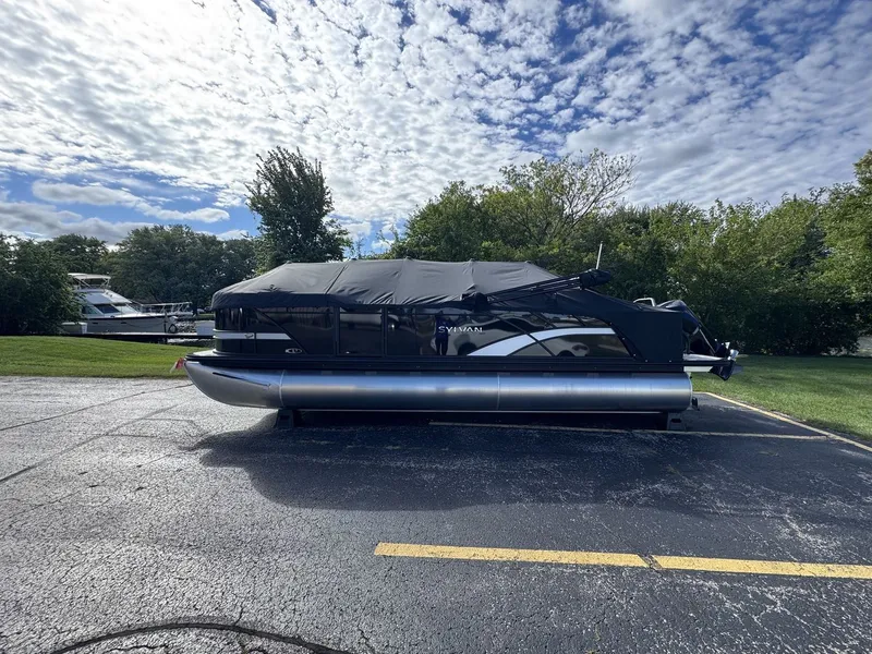 Slide: The Image of A 2026 Sylvan L3 DLZ pontoon boat is parked on a lot, surrounded by trees. - 30