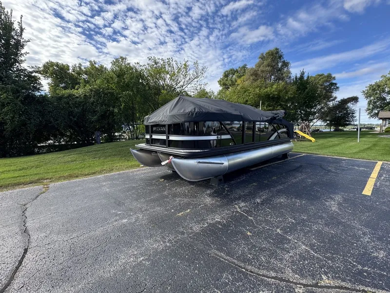 Slide: The Image of A 2026 Sylvan L3 DLZ pontoon boat is parked on a lot, surrounded by trees and grass. - 31
