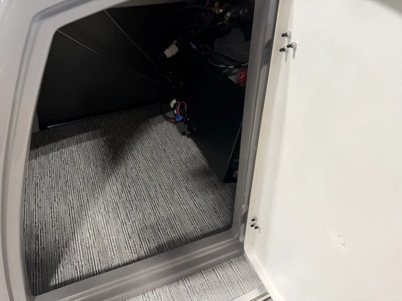 Slide: The Image of An open storage compartment with gray carpet flooring and visible wiring inside. - 13