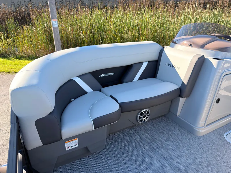 Slide: The Image of The image shows a sleek, cushioned seating area on a Sylvan boat, surrounded by reeds. - 10
