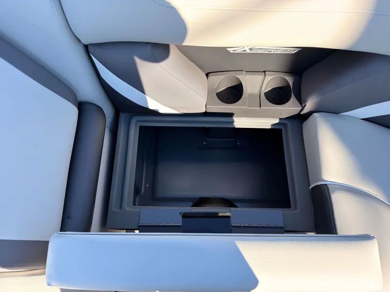 Slide: The Image of An open storage compartment on a Sylvan MIRAGE X3 DLZ BAR boat, surrounded by cushioned seating. - 16