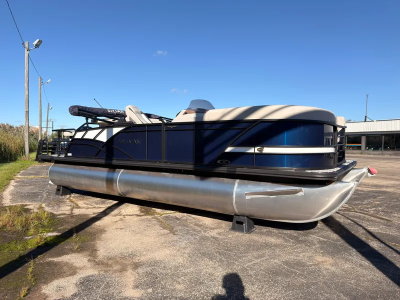 Slide: The Image of A Sylvan MIRAGE X3 DLZ BAR pontoon boat is parked on a lot under a clear sky. - 7
