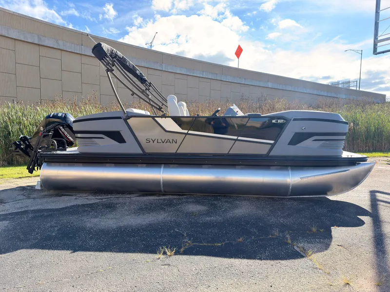 Slide: The Image of The image shows a 2027 Sylvan R-20 Q DH pontoon boat parked on an asphalt lot. - 2