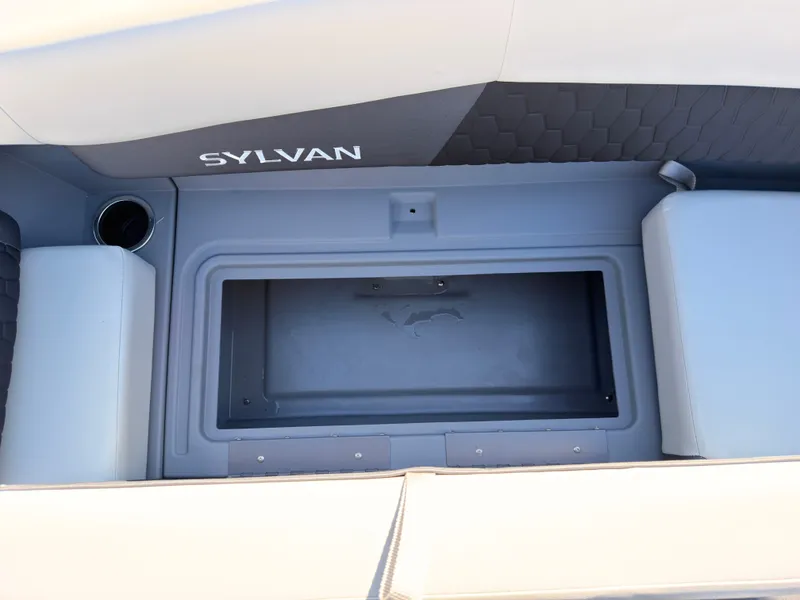 Slide: The Image of The image shows a gray storage compartment on a Sylvan boat with cushioned seating. - 14