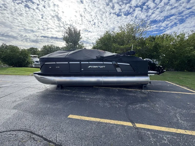 Slide: The Image of A 2027 Starcraft EXS 3 DL pontoon boat is parked, covered with a black tarp. - 30