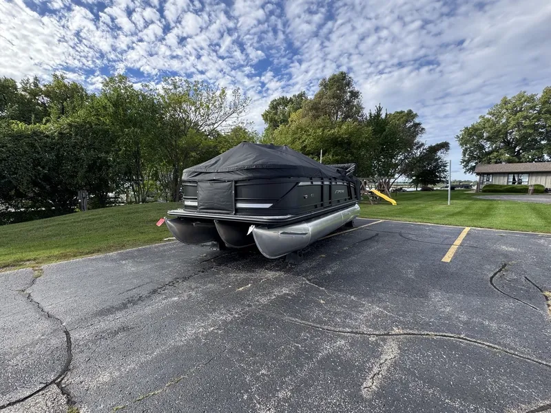 Slide: The Image of A 2027 Starcraft EXS 3 DL pontoon boat is parked, covered with a black tarp. - 31