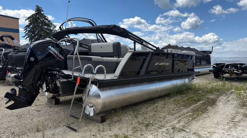 Slide: The Image of A 2027 Starcraft EX 20 Q DH pontoon boat is on dry land. It features an outboard motor and ladder. - 3