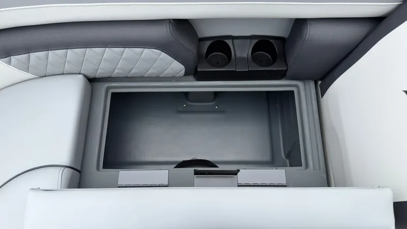 Slide: The Image of An open storage compartment on a 2027 Starcraft EXS 3 DL boat, featuring two cup holders. - 20