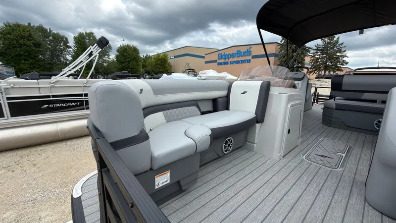 Slide: The Image of The image shows a 2027 Starcraft EXS 3 DL pontoon boat with gray seating and a covered area. A boat dealership is visible in the background. - 8