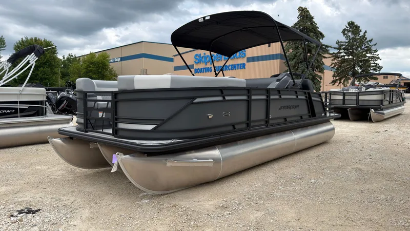 Slide: The Image of A 2027 Starcraft EXS 3 DL pontoon boat is parked on gravel in front of a building. - 2