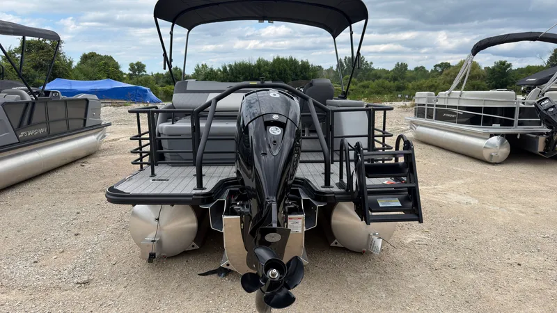 Slide: The Image of A 2027 Starcraft EXS 3 DL pontoon boat with an outboard motor, parked on a gravel lot. - 5