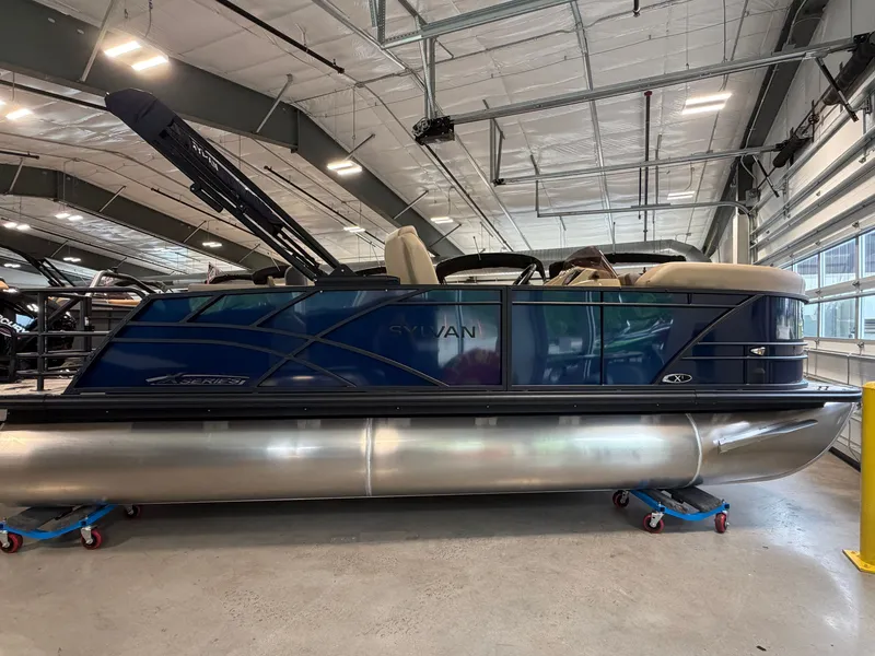 Slide: The Image of A modern pontoon boat with a blue hull and beige interior, stored indoors on rollers. - 4