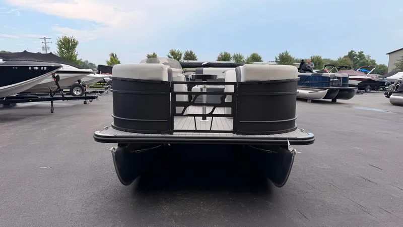 Slide: The Image of A 2027 Starcraft EX 20 Q DH pontoon boat is parked. It features a black railing and white seats. - 2