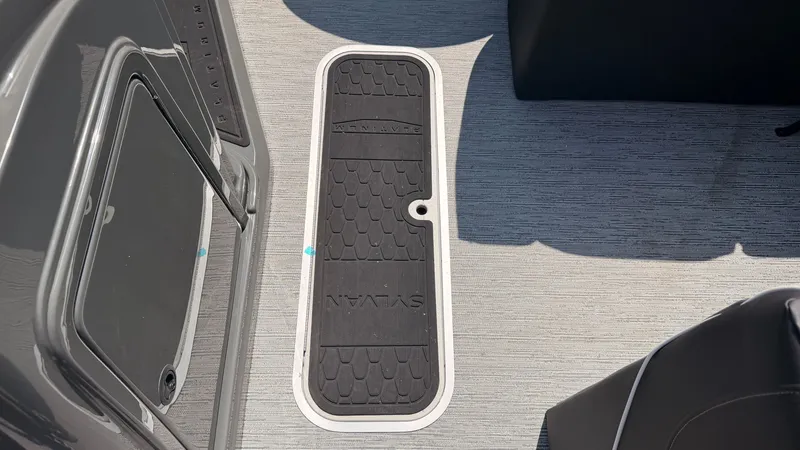 Slide: The Image of The image shows the floor of a Sylvan MIRAGE X3 DLZ BAR boat with a textured cover. - 23