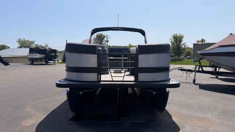 Slide: The Image of The image shows a Sylvan pontoon boat with a sleek design, parked on a lot. - 2