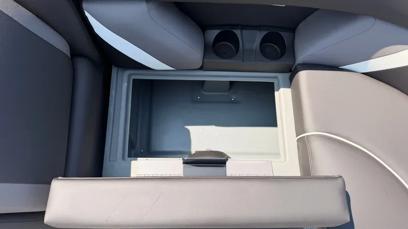 Slide: The Image of An open storage compartment on a boat with gray upholstery and cup holders. - 14
