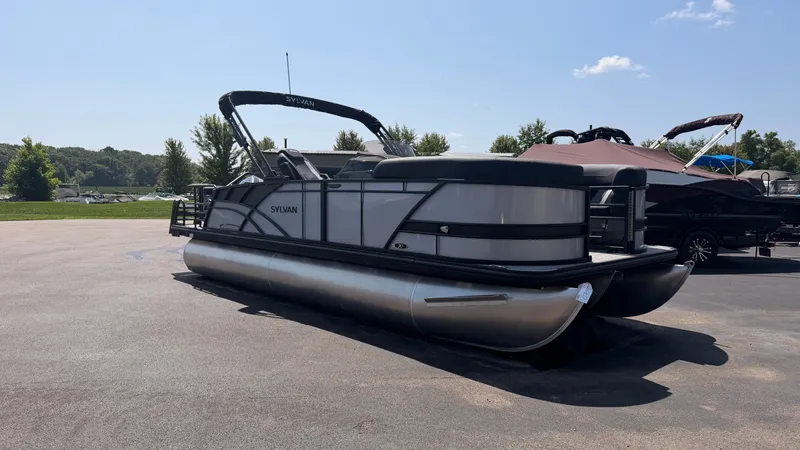 Slide: The Image of A modern Sylvan pontoon boat, model MIRAGE X3 DLZ BAR, is parked under a clear blue sky. - 1