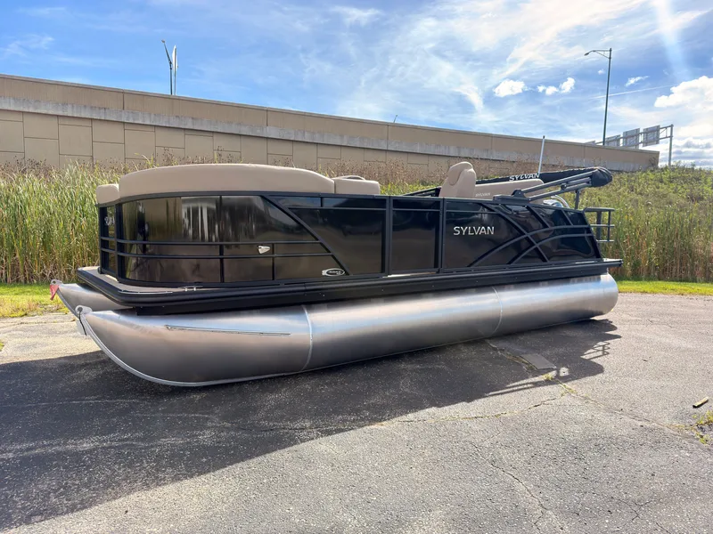 Slide: The Image of Sylvan Mirage 8520 CLZ DH 2027 on a parking lot, featuring a black hull and silver pontoons. - 1
