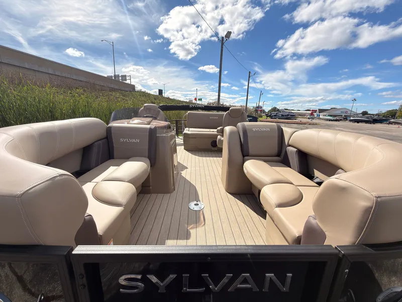 Slide: The Image of Sylvan Mirage 8520 CLZ DH 2027 with beige upholstered seats and open deck under a blue sky. - 9