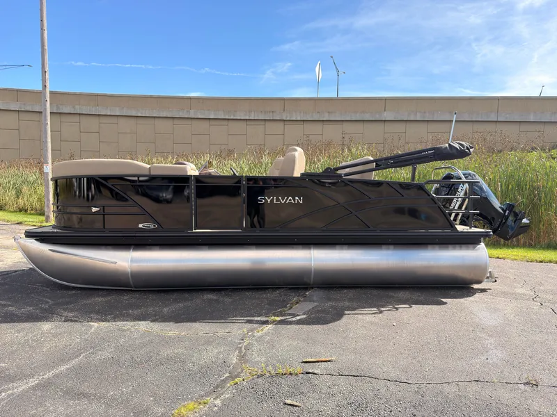 Slide: The Image of Sylvan Mirage 8520 CLZ DH 2027 on a parking lot, featuring a black hull and beige seating. - 2
