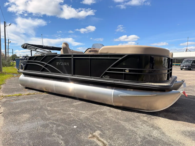 Slide: The Image of Sylvan Mirage 8520 CLZ DH 2027 on a parking lot, featuring a black hull and beige canopy. - 7