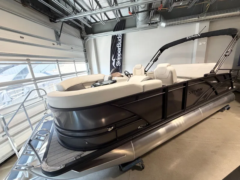 The Image of A Sylvan Mirage 8520 CLZ DH pontoon boat in a showroom. It features white seating and a black railing. - 0