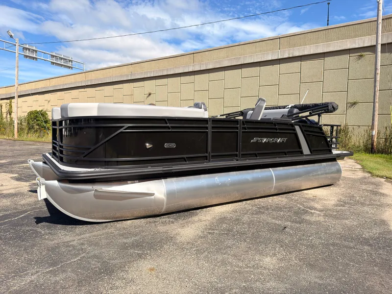 The Image of A 2027 Starcraft EXS 1 Q DH pontoon boat is parked on a lot in front of a building. - 0