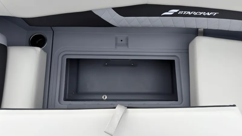 Slide: The Image of A gray storage compartment on a Starcraft boat with cushioned seats and a cup holder. - 25