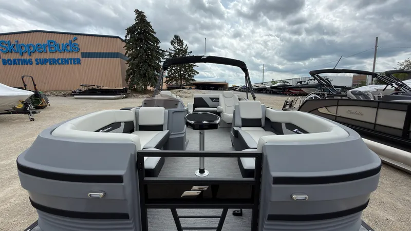 Slide: The Image of The image shows a modern pontoon boat with gray upholstery and a central table, situated at a boatyard. - 13