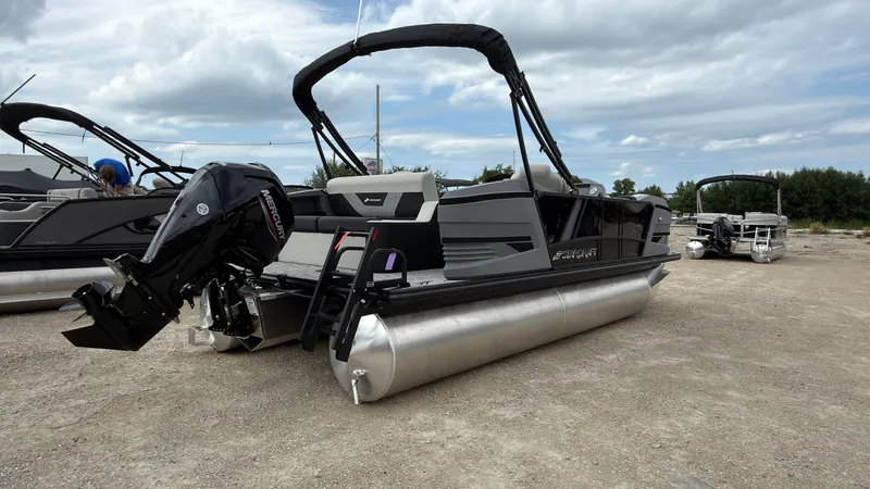Slide: The Image of A modern pontoon boat with a powerful outboard motor, parked on a gravel lot under cloudy skies. - 7