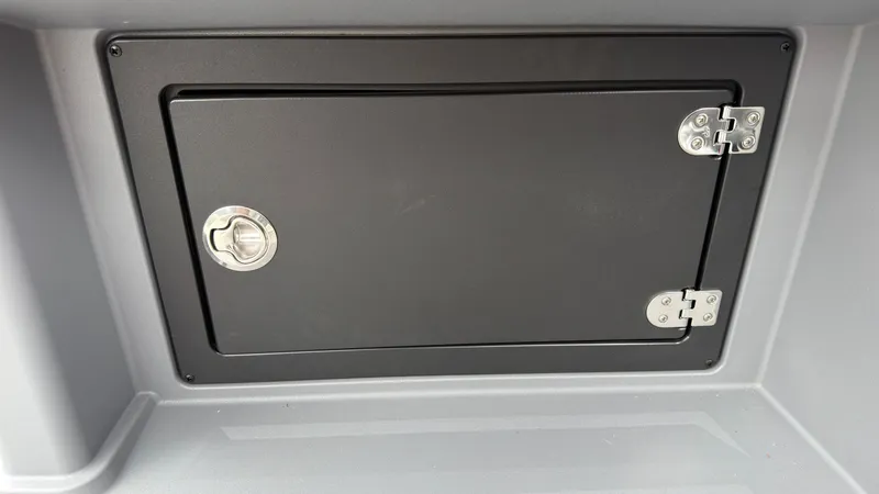 Slide: The Image of A black storage compartment with silver hinges and a round handle on a boat. - 40