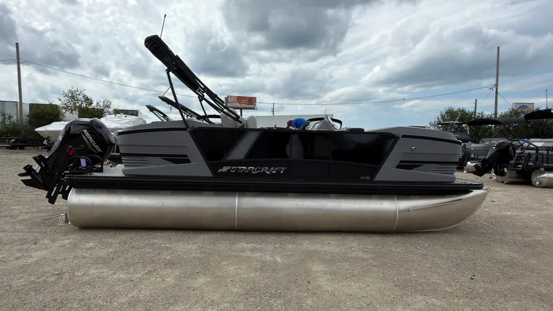 Slide: The Image of A modern pontoon boat with a gray hull and black superstructure, parked on a gravel lot. - 8