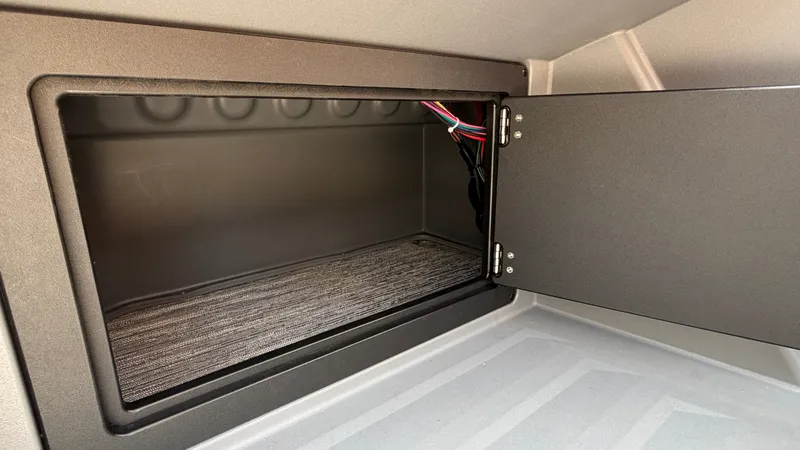 Slide: The Image of An open storage compartment with carpeted flooring and visible wiring inside. - 35