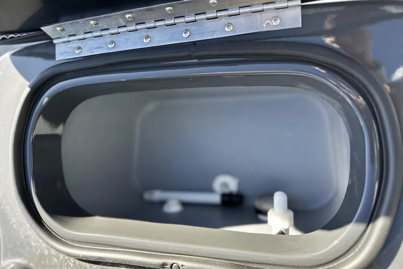 Slide: The Image of Open storage compartment of 2026 Avid 20 Rogue CC boat, featuring metal hinge detail. - 14