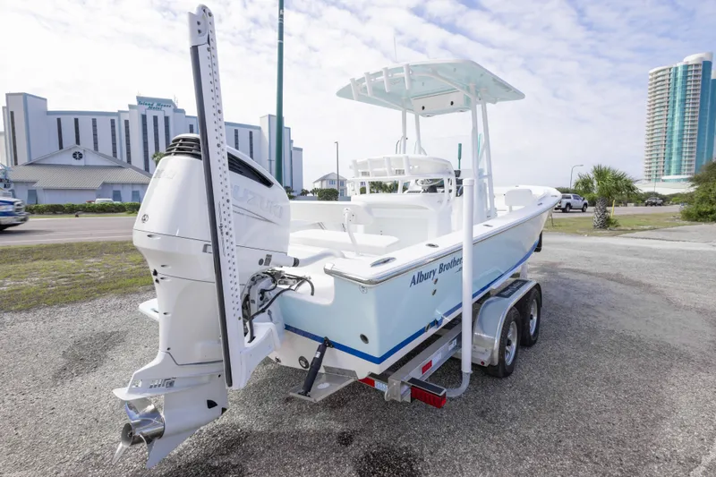 Slide: The Image of 2026 Albury Brothers 23 Forward Seating boat on trailer, parked near modern buildings. - 11
