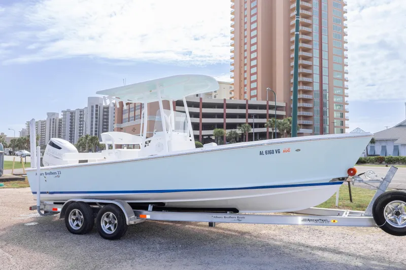 Slide: The Image of 2026 Albury Brothers 23 Forward Seating boat on trailer, parked near high-rise buildings. - 6