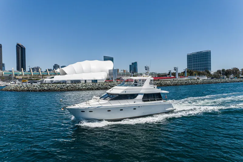 The Image of 1999 Carver 530 Voyager Pilothouse yacht cruising near urban waterfront skyline. - 0