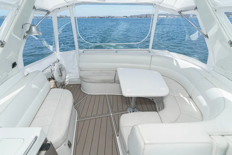 Slide: The Image of 1999 Carver 530 Voyager Pilothouse interior with white seating and table, overlooking the ocean. - 11