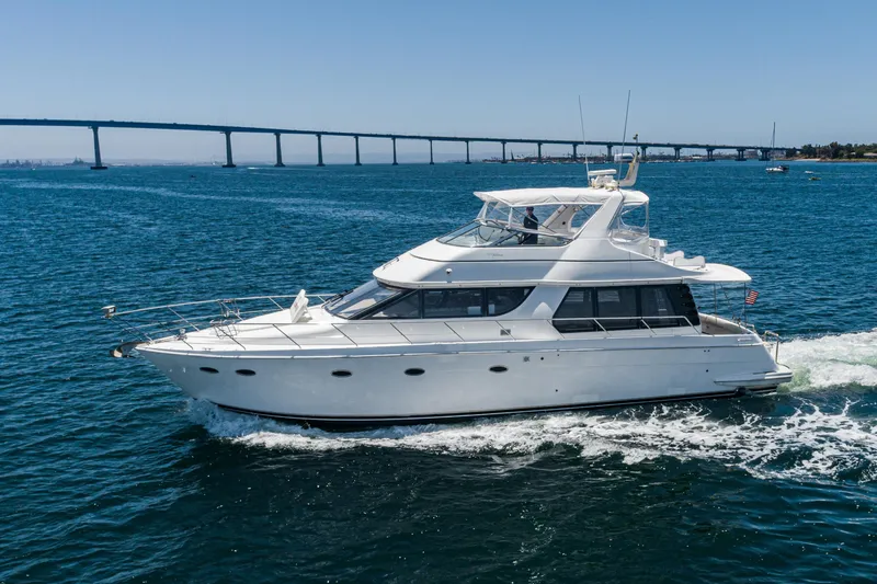 Slide: The Image of 1999 Carver 530 Voyager Pilothouse yacht cruising on blue water near a bridge. - 43