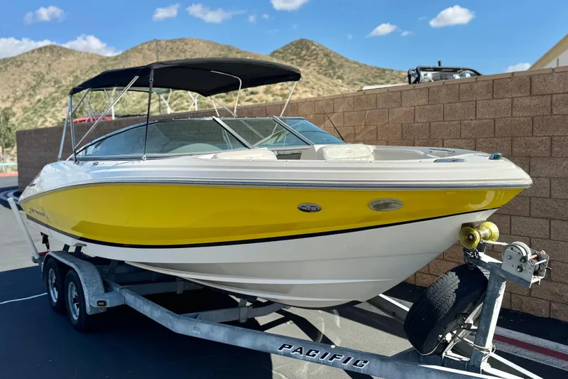 Slide: The Image of 2005 Regal 2200 Bowrider boat with yellow hull on trailer, mountainous background. - 1