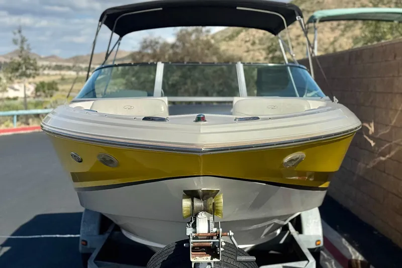 Slide: The Image of 2005 Regal 2200 Bowrider boat on trailer, yellow hull, parked outdoors. - 2