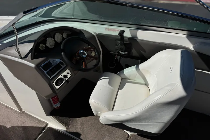 Slide: The Image of 2005 Regal 2200 Bowrider boat cockpit with steering wheel and white captain's chair. - 28