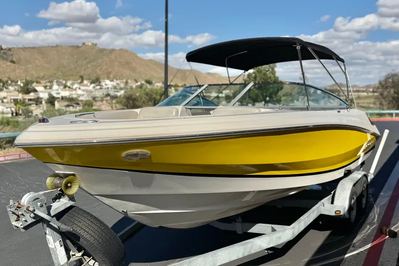 Slide: The Image of 2005 Regal 2200 Bowrider boat with yellow hull on trailer, scenic background. - 3