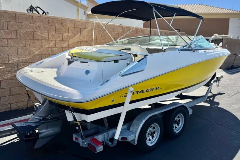 Slide: The Image of 2005 Regal 2200 Bowrider boat with yellow hull on a trailer, parked outdoors. - 5