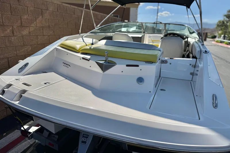 Slide: The Image of 2005 Regal 2200 Bowrider boat with yellow seating, parked on a trailer. - 6