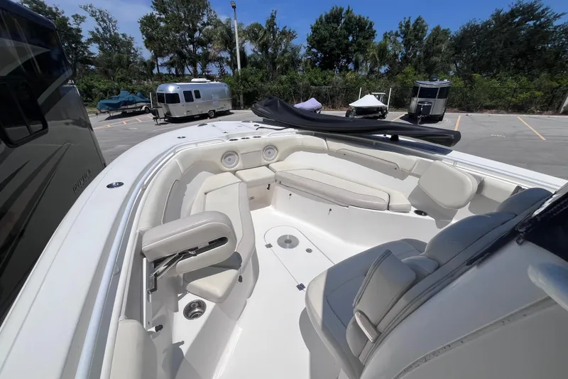 Slide: The Image of 2017 Tidewater 280 CC Adventure boat interior with seating and storage, parked outdoors. - 17
